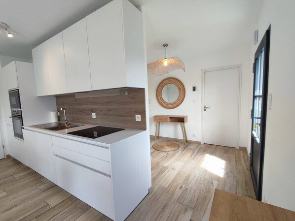 Eine moderne Küche mit weißen Schränken, einer Holzrückwand und einer eingebauten Kochinsel mit Spüle.