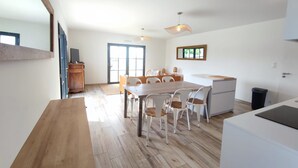 A modern kitchen with a dining area, wooden flooring, and a large window. - Le 4 Pors Carn – walk to the beach, peaceful, sea view (Penmarch)