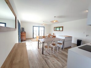 Eine moderne Küche mit Essbereich, Holzboden und einem großen Fenster.