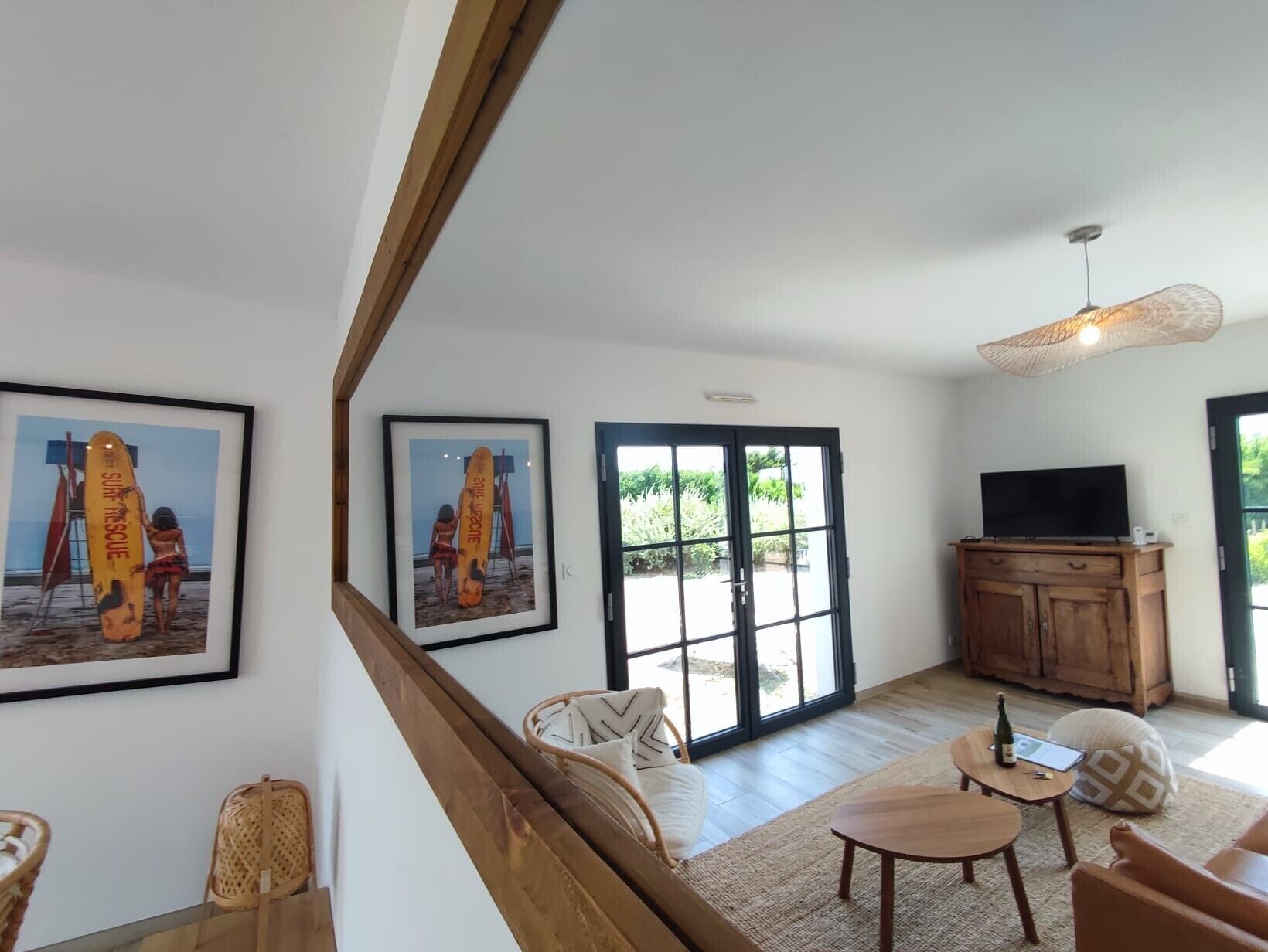 A spacious living room with a large window, a television, and a wooden cabinet.