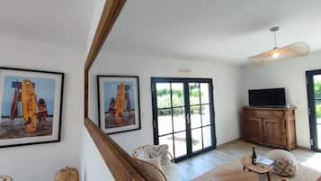 A spacious living room with a large window, a television, and a wooden cabinet.