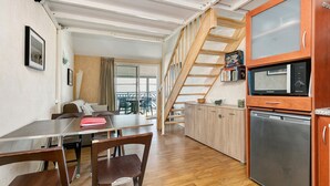 Una cocina moderna con una escalera de madera, un comedor con mesa y sillas, y vistas al exterior.