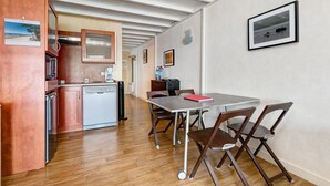 Una cocina compacta equipada con lavavajillas, microondas y un pequeño comedor con mesa y sillas.
