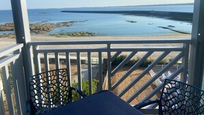 Un espacio al aire libre techado con vista a una costa rocosa y agua tranquila.