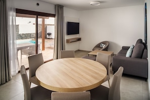Ein modernes Wohnzimmer mit einem runden Holztisch, einem grauen Sofa und einem flachbildfernseher an der Wand.