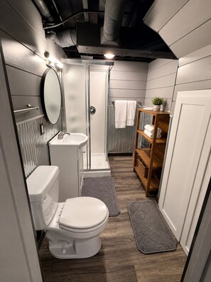 A compact bathroom with a toilet, sink, and shower.