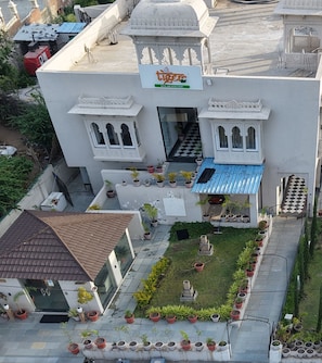A hotel with a central entrance, potted plants, and a blue awning. - The Dabs Tiger Tails Hotel (Kumbhalgarh)