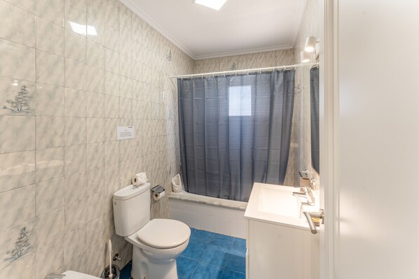 A bathroom with a toilet, a bathtub, and a sink.