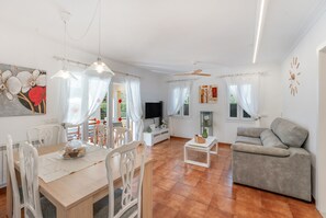 Un espai ampli de estar per a viure amb taula de menjador, sofà i televisió.
