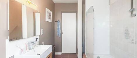 A modern bathroom with a sink, mirror, and shower.