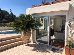A modern house with a pool, a large potted plant, and a sliding glass door leading to a patio. - Luxury Penthouse with Private Pool, Terrace, and Stunning Views (Athens)
