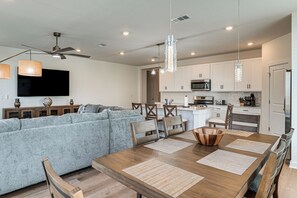 Una cocina moderna con armarios blancos, una mesa de comedor con individuales y un ventilador de techo.