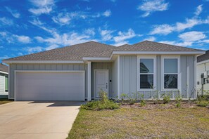 Ein Bungalow mit Garage, Eingangstür und kleinem Garten mit jungen Pflanzen.