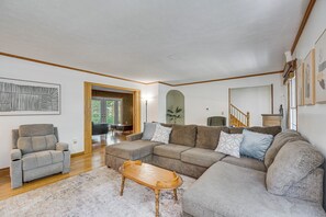 A living room with a sectional sofa, a recliner, a wooden coffee table, and a large window. - Families Welcome! Extended-stay Haven in Medina (Medina)