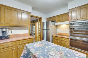 A kitchen with wooden cabinets, a stainless steel refrigerator, an oven, and a floral tablecloth. - Families Welcome! Extended-stay Haven in Medina (Medina)