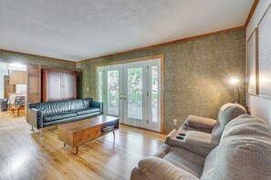 A living room with a sofa, coffee table, and a cabinet. There is a door with glass panels and a view outside. - Families Welcome! Extended-stay Haven in Medina (Medina)