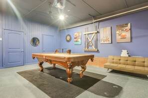 Ein Billardtisch in einem Raum mit blauen Wänden, einer Couch und Kunstwerken.