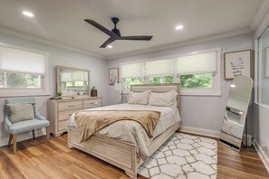 Ein Schlafzimmer mit Bett, Stuhl, Kommode, Deckenventilator und einem Fenster mit Jalousien.