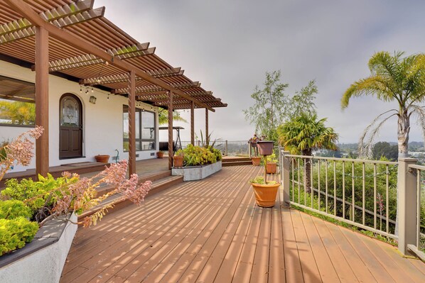 A wooden deck with planters, a pergola, and a view of the landscape. - Ocean View + Private Garden: Santa Cruz Home (Santa Cruz)