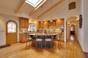 A spacious kitchen with wooden cabinets, a central island with bar stools, and a skylight. - Ocean View + Private Garden: Santa Cruz Home (Santa Cruz)