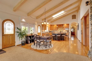 A spacious kitchen with wooden beams, a dining area with a round table, and a stone wall. - Ocean View + Private Garden: Santa Cruz Home (Santa Cruz)