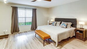 A bedroom with a bed, bench, bedside tables, a ceiling fan, and a window with curtains. - Satx Family Getaway w/ Patio, Grill & Yard! (San Antonio)