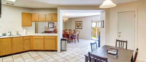 A kitchen with wooden cabinets, a dining area with a table and chairs, and a hallway leading to a door.