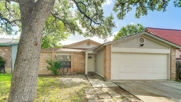 A residential house with a garage, brick exterior, and a large tree in the front yard. - Satx Family Getaway w/ Patio, Grill & Yard! (San Antonio)