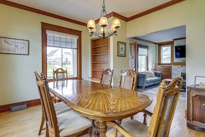 A dining room with a wooden table and chairs, a chandelier, and a view of the outside. - Historic Home on Beaver Dam Lake w/ Seasonal Dock (Cumberland)