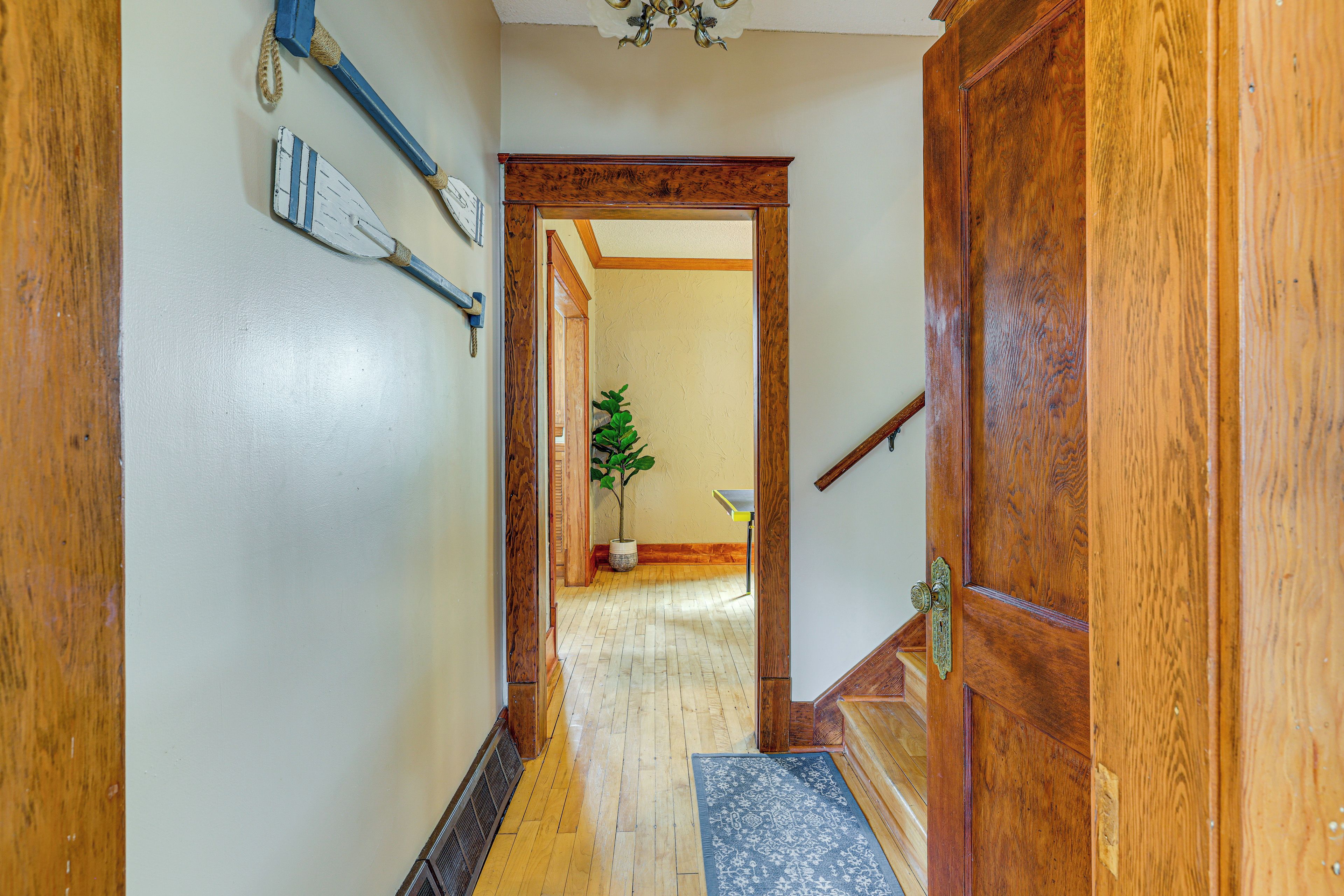 A wooden hallway with a door, a plant, and a small table.
