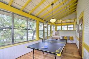 Um quarto com mesa de pingue-pongue, janelas amplas e teto amarelo.