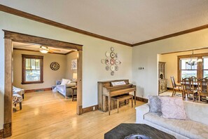 A spacious living room with a wooden piano, a sofa, and a dining area with wooden furniture.