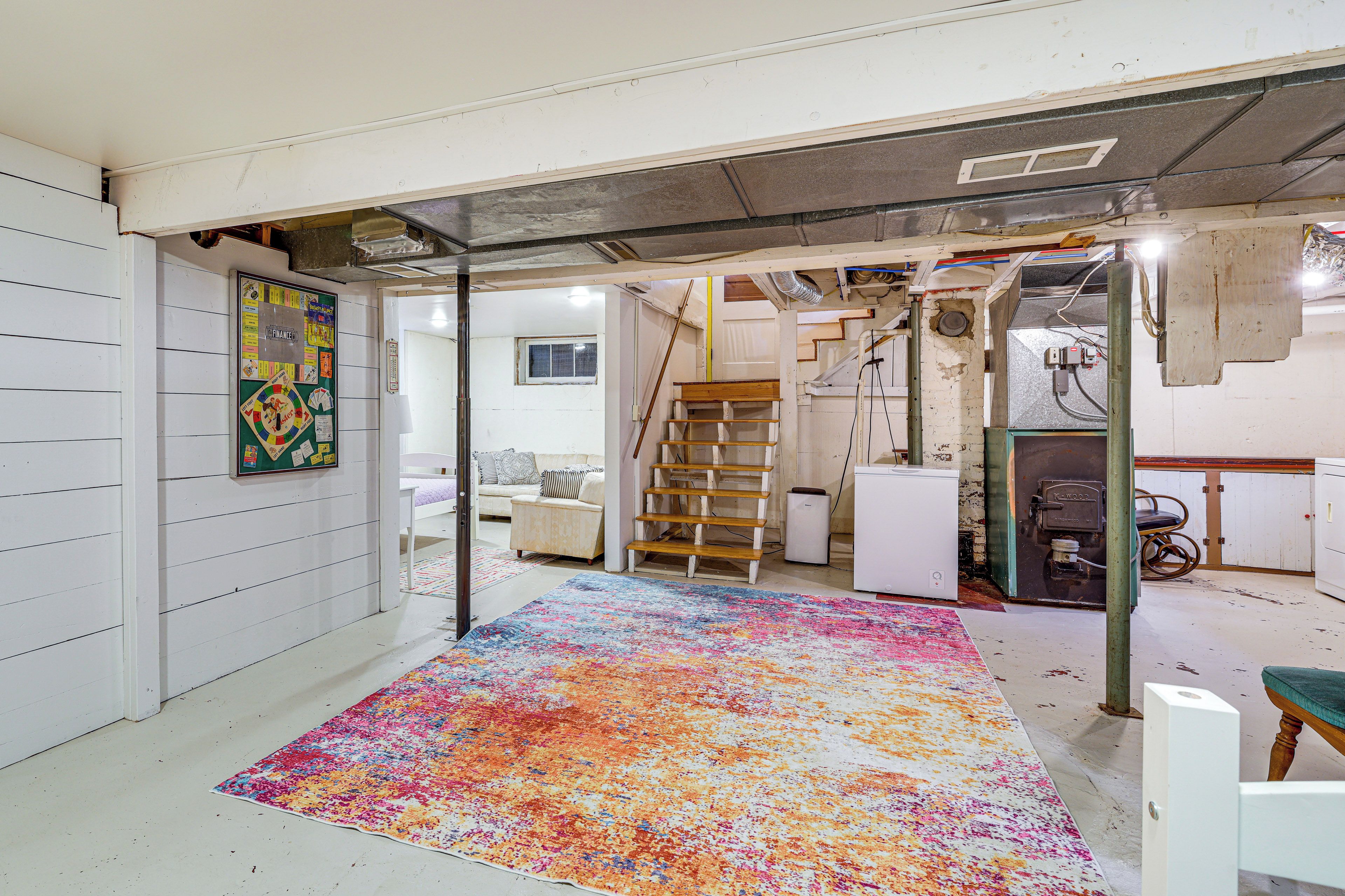 A room with a colorful rug, a white couch, a wooden chair, and a small table.