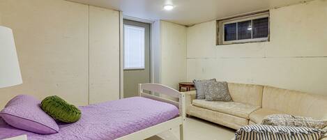 A small, single-room accommodation with a bed, a sofa, and a window.