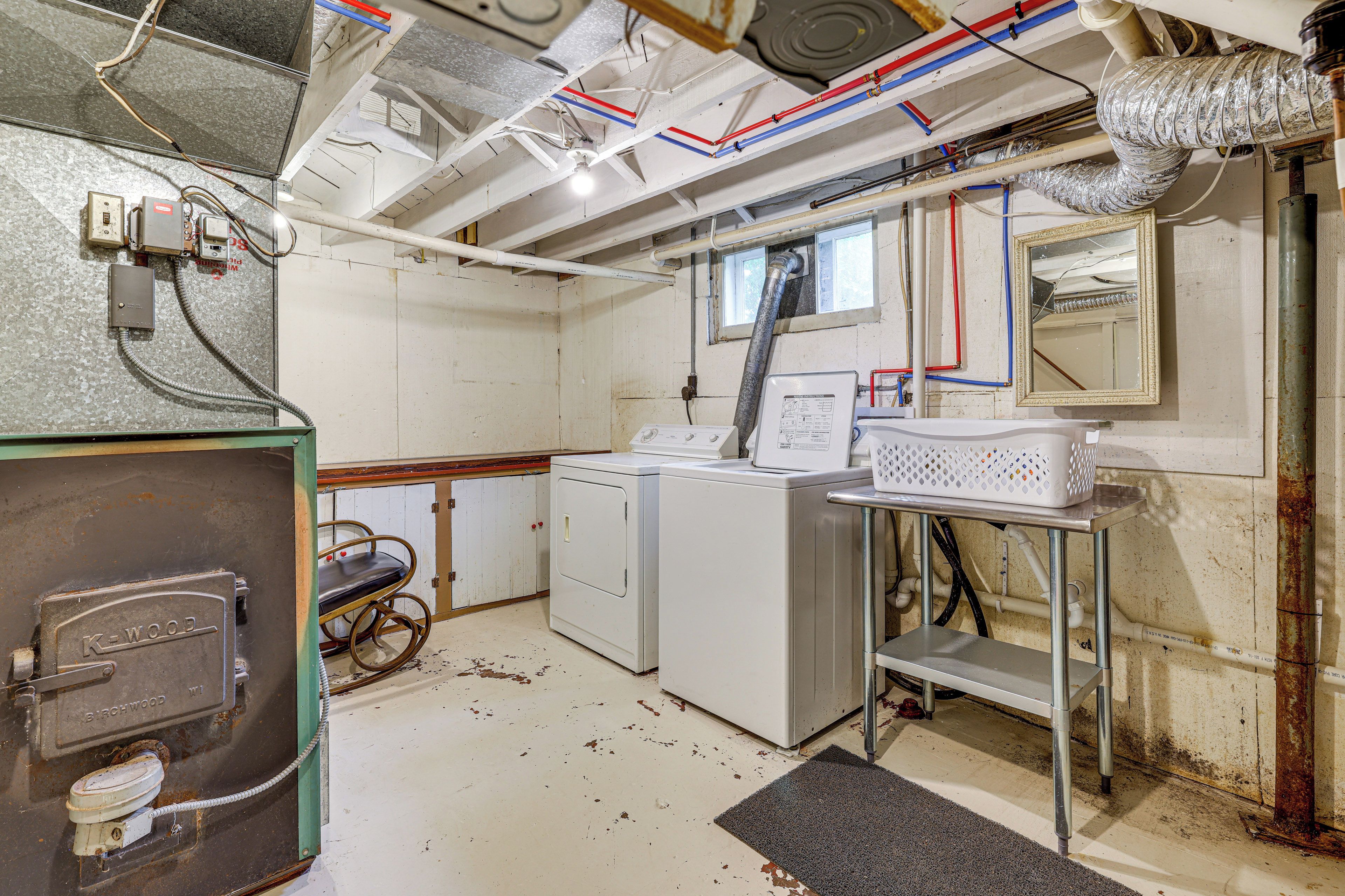 A laundry room with a washing machine, dryer, and various pipes and ducts.