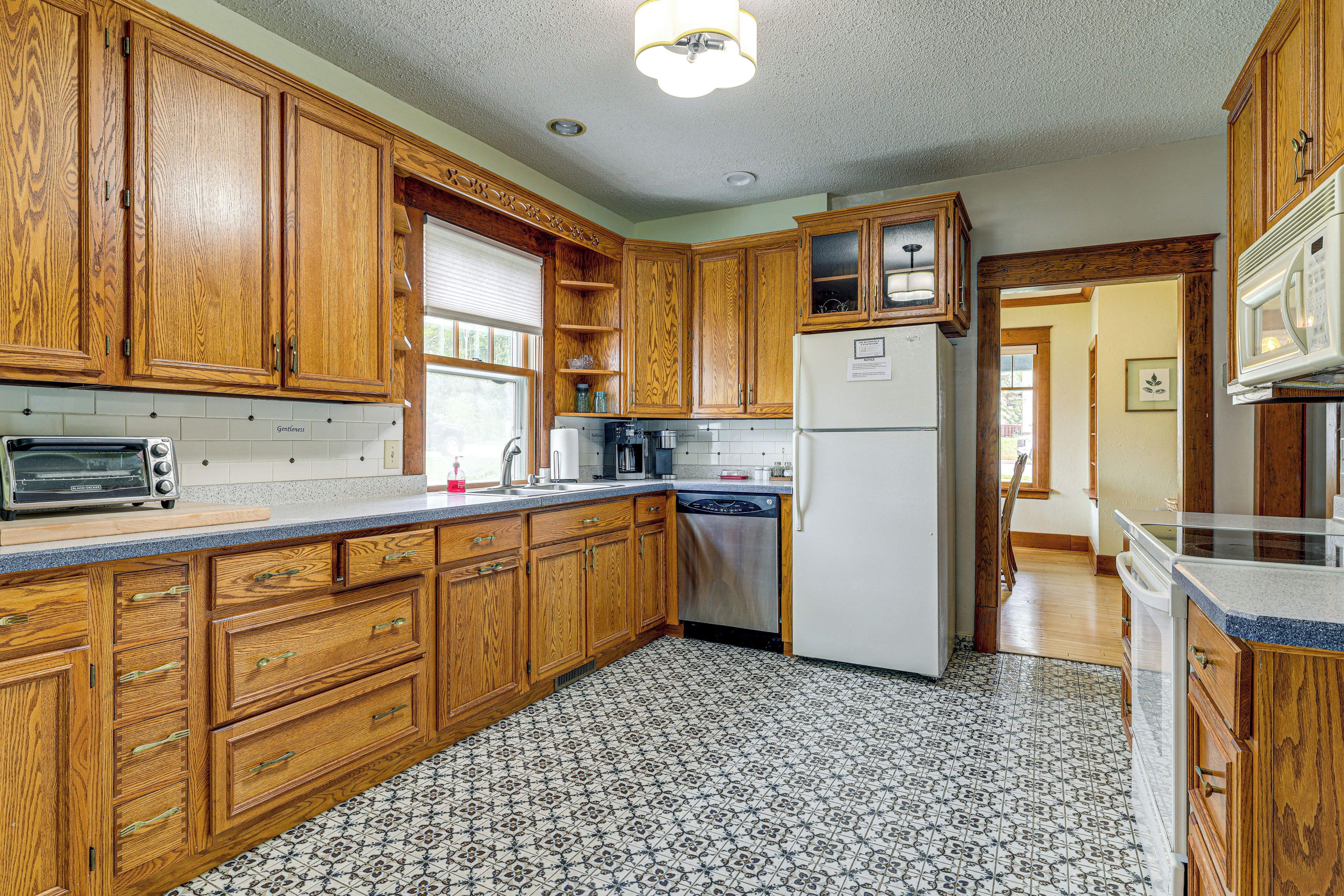 A kitchen with wooden cabinets, a stainless steel refrigerator, and a patterned tile floor.