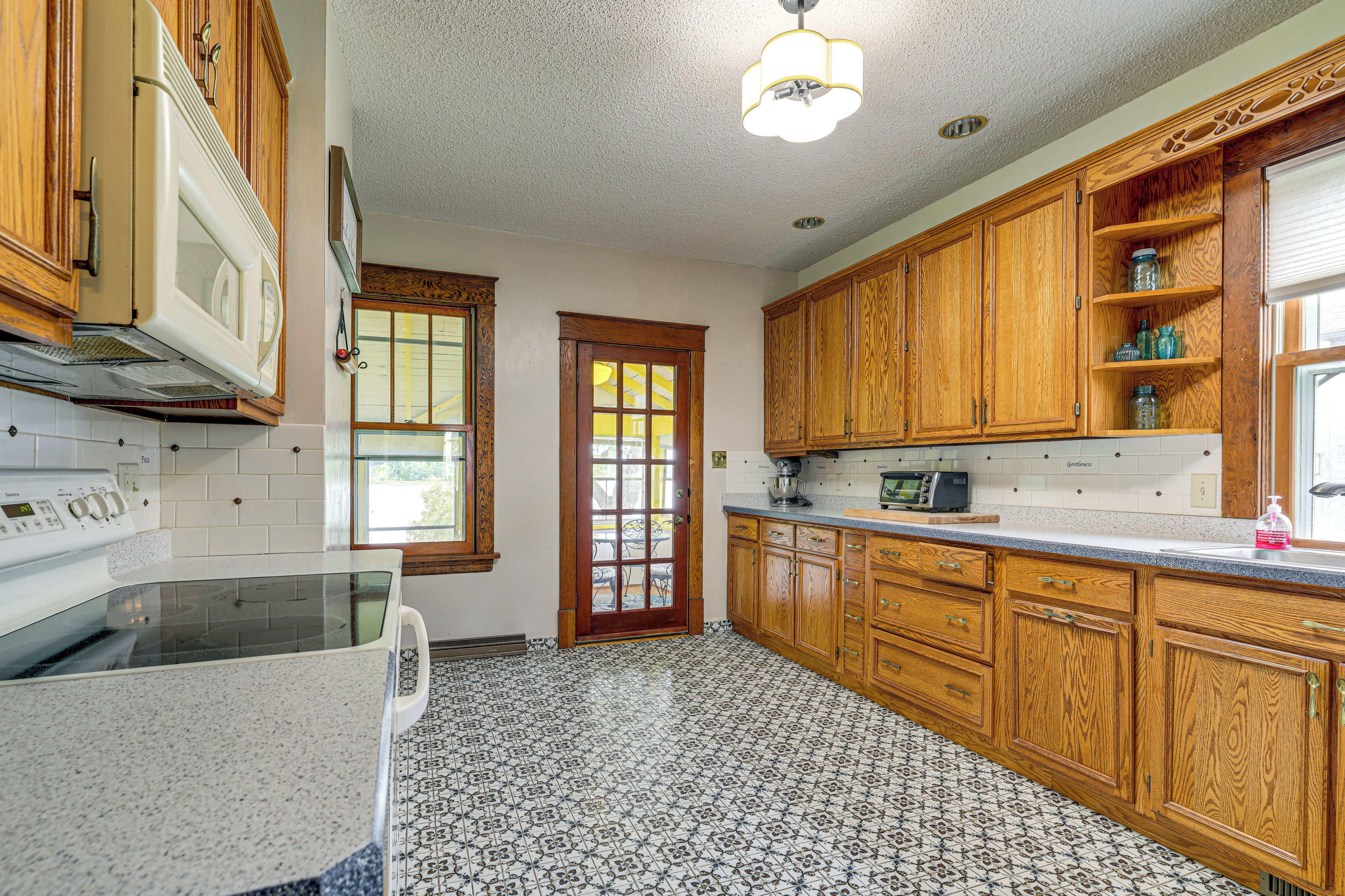 A kitchen with wooden cabinets, a microwave, a stove, and a window with a view.