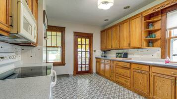 A kitchen with wooden cabinets, a microwave, a stove, and a window with a view.