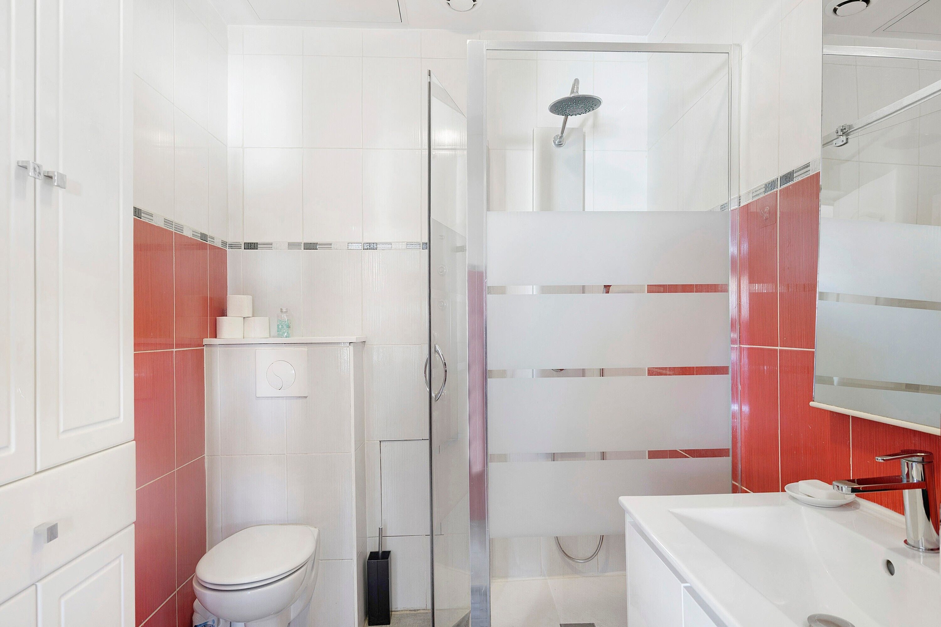 A bathroom with a toilet, shower, and sink.