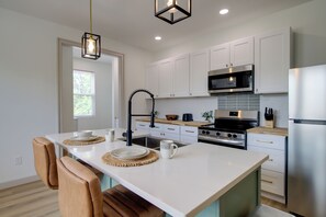 A modern kitchen with white cabinets, stainless steel appliances, and a central island with seating. - Knoxville Extended Base! 3 Mi to Med Center (Knoxville)