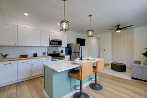 A modern kitchen with white cabinets, a central island with bar stools, a microwave, and a refrigerator. - Knoxville Extended Base! 3 Mi to Med Center (Knoxville)