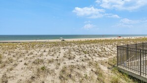 Ein Strand mit sandigem Ufer, einer Holzpromenade und einem Metallzaun.