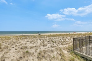 A beach with a sandy area, a wooden walkway, and a metal fence. - Premier Beachfront Location in Seaside Heights (Seaside Heights)
