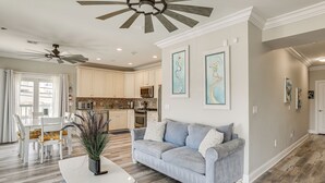 Ein modernes Wohnzimmer mit grauem Sofa, weißem Couchtisch und einem Essbereich mit weißen Stühlen.