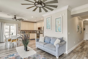A modern living room with a gray sofa, white coffee table, and a dining area with white chairs. - Premier Beachfront Location in Seaside Heights (Seaside Heights)