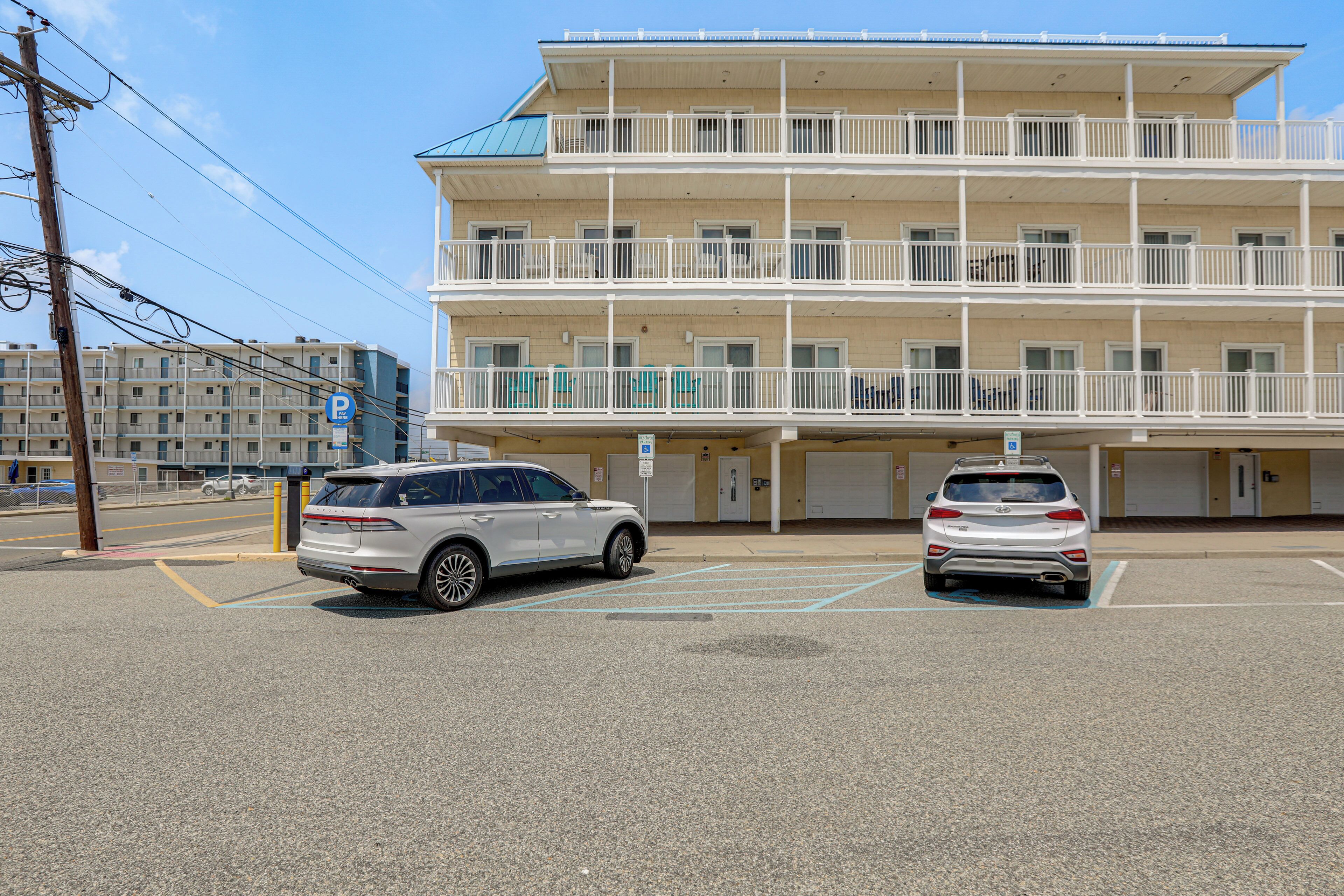 Un edificio de varios pisos con balcones, espacios de estacionamiento y un cielo despejado.