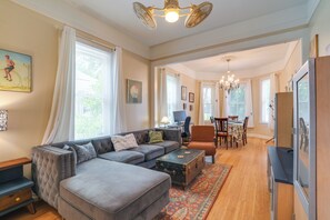 Ein Wohnzimmer mit Ecksofa, einer Essecke mit Tisch und Stühlen, einem Vintage-Koffer und einer Chandelier.