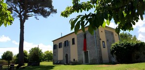 Un edificio con fachada de piedra, una puerta roja y un pequeño arco de entrada.