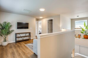 A modern interior with a flat-screen TV, wooden flooring, a staircase, and a potted plant.