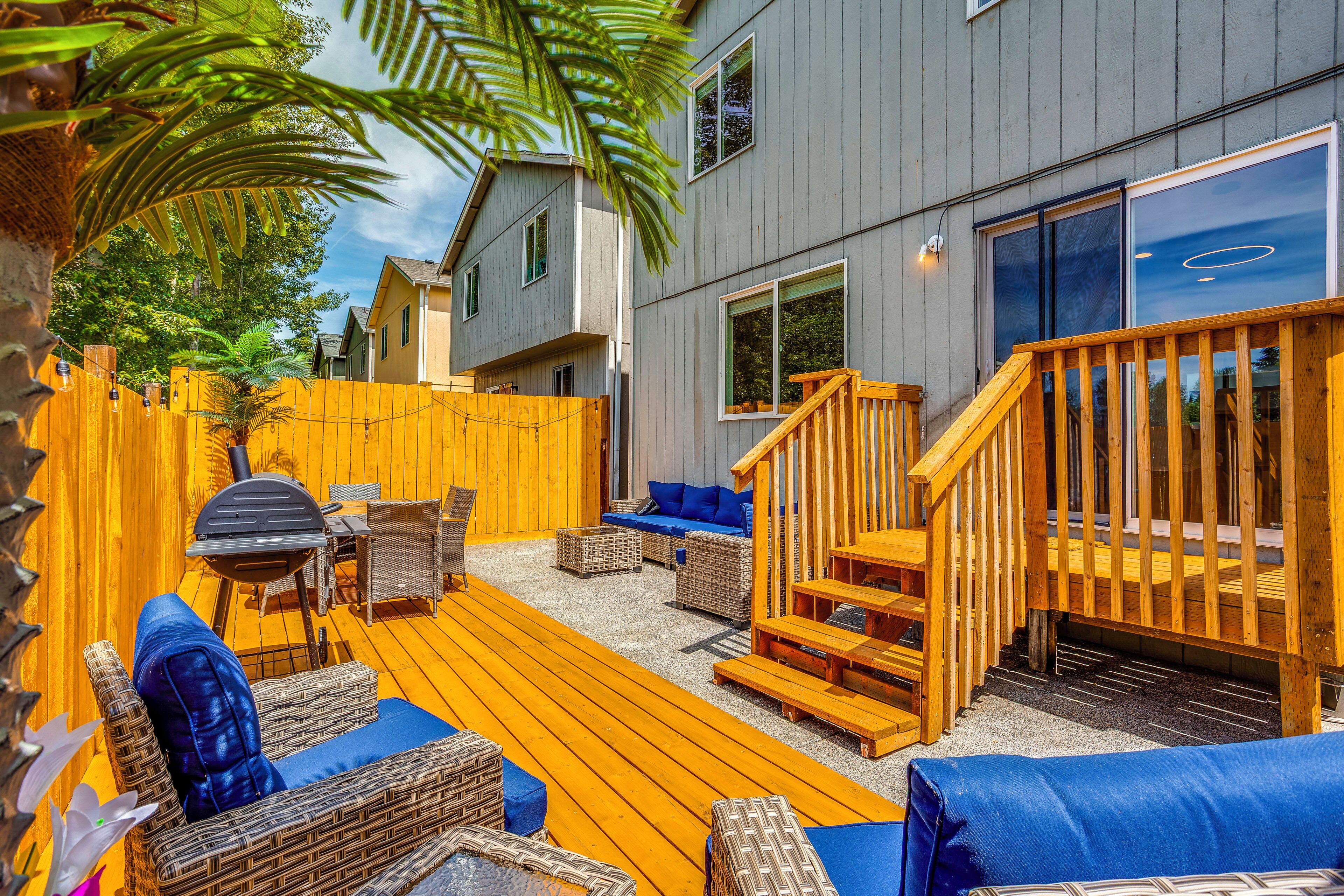 A deck with wicker furniture, a wooden staircase, and a view of a building with large windows.